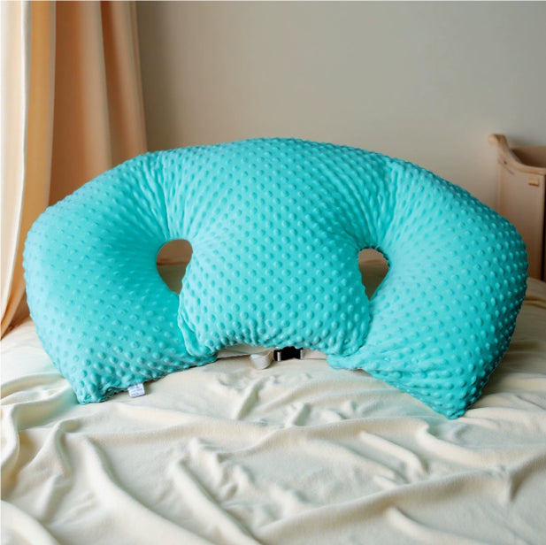 Infant Multifunctional Nursing Pillow Cushion in soft turquoise fabric on a bed.